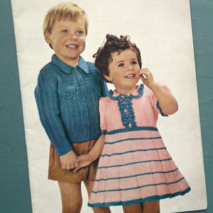 May include: A vintage knitting pattern book cover featuring two children wearing knitted garments. The book is titled "Woolworth's Toddlers' Book 1/-" and states "Knitted Garments for Toddlers Aged 2 to 5 Years".