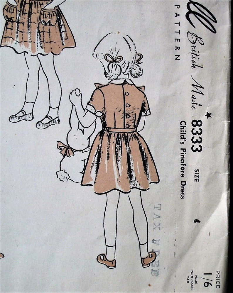 Op de afbeelding: Vintage naaipatroon voor een kinder pinafore jurk. De illustratie toont een meisje in een lichtbruine jurk met een geplooide rok, met een knuffelkonijn. Het patroon is gemarkeerd met "British Made 8333, Maat 4".