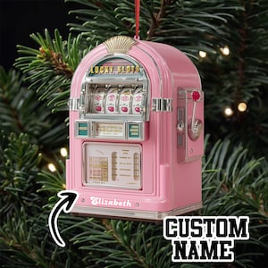 May include: Pink slot machine Christmas ornament with the text "Lucky Slots" and "Elizabeth" on the front. The ornament has a gold-colored top and a red pull lever on the side. The words "CUSTOM NAME" are also visible.