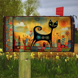 May include: A black mailbox with a whimsical cat design. The artwork features a black cat silhouette with floral accents against a colorful background of flowers, buildings, and a sun. The mailbox has a red flag and is mounted on a wooden post.