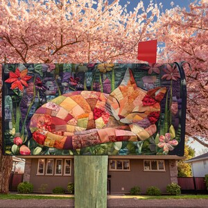 May include: A decorative mailbox featuring a patchwork cat design. The cat is curled up and sleeping, with a mix of orange, red, and brown fabric pieces. The background includes flowers and greenery, with a red flag on top.