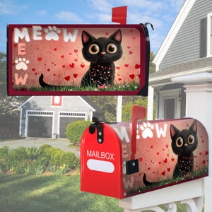 以下が含まれることがあります： 大きな目をした黒猫がハートと「MEOW」の文字に囲まれた装飾的なデザインの赤い郵便受け。 郵便受けには赤い旗と側面に「MAILBOX」の文字があります。