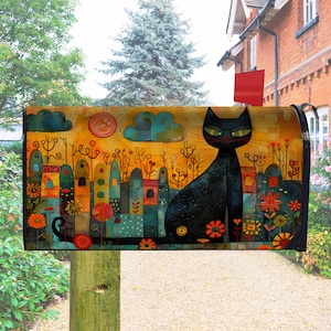 May include: A decorative mailbox featuring a black cat with green eyes, sitting against a colorful backdrop. The design includes a stylized cityscape with orange, teal, and yellow hues, and floral accents. The mailbox is mounted on a wooden post.