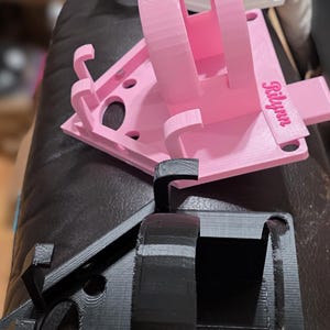 May include: A collection of 3D-printed prototypes in various stages of completion. The prototypes are in pink, white, and black. The word "PROTOTYPES" is printed at the top of the image. One pink prototype has the name "Rilynn" printed on it.