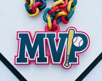 Może przedstawiać: Zawieszka o tematyce baseballowej z literami "MVP" w kolorze granatowym z czerwonym obrysem. Obok liter znajduje się kij i piłka do baseballu. U góry łańcuch z czerwonych, żółtych i turkusowych ogniw. Zawieszka jest na białym tle.