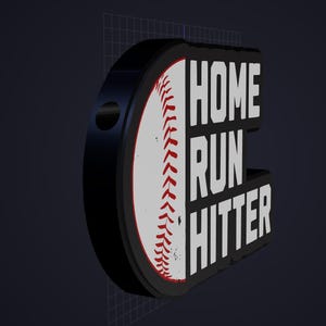 May include: A three-dimensional sign featuring a white baseball with red stitching on the left side and the bold white text HOME RUN HITTER on a black background on the right side. The object has a thick black border and a circular hole on the side.