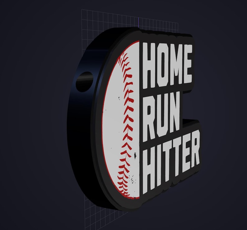May include: A three-dimensional sign featuring a white baseball with red stitching on the left side and the bold white text HOME RUN HITTER on a black background on the right side. The object has a thick black border and a circular hole on the side.