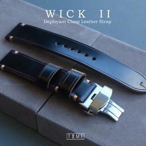 May include: Black leather watch strap with gold stitching and a silver deployant clasp. The strap is labeled "WICK II Deployant Clasp Leather Strap". The brand logo "T X M E" is visible at the bottom.