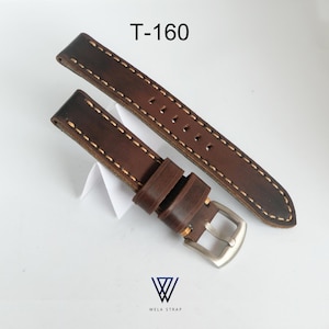 May include: A brown leather watch strap with cream-colored stitching. The strap has a silver-colored buckle and is labeled "T-160". The Wela Strap logo is visible at the bottom.