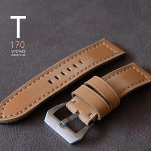May include: A light brown leather watch strap with white stitching and a silver buckle. The strap has multiple holes for adjustment and the text "T 170 VINTAGE watch strap" is visible.