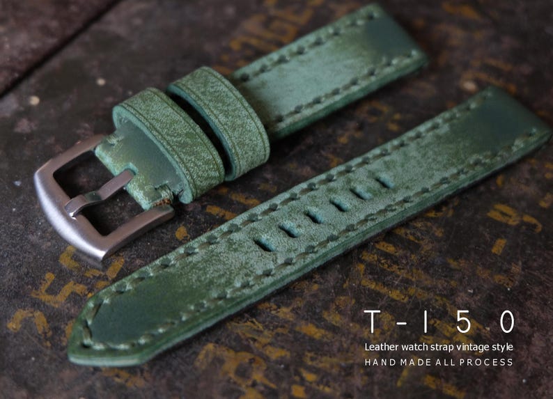 May include: Green leather watch strap with a vintage style, featuring a silver buckle and visible stitching. The strap has a distressed finish and the text "T-150 Leather watch strap vintage style HAND MADE ALL PROCESS".