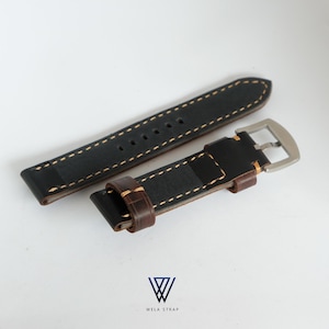 May include: Black and brown leather watch strap with cream stitching. The strap has a silver buckle and is made of two pieces. The brand name "WELA STRAP" is printed at the bottom of the image.