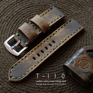 May include: Distressed brown leather watch strap with green stitching and a silver buckle. The strap features the text "T-110 Leather watch strap vintage style HAND MADE ALL PROCESS". The watch strap is a vintage style.
