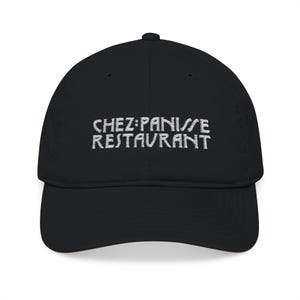 May include: Black baseball cap with a curved peak. The cap has the embroidered text "CHEZ PANISSE RESTAURANT" in white across the front. The hat is made of a soft material and has a classic, casual style.