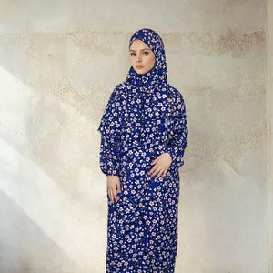 May include: A long blue dress with a white floral pattern. The dress has long sleeves and a high neckline. The dress is made of a soft, comfortable fabric.