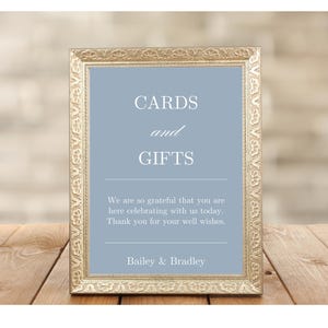 K&ouml;nnte beinhalten: Ein goldfarbener Rahmen mit einem hellblauen Hintergrund und dem Text "CARDS and GIFTS". Das Schild enth&auml;lt auch den Text "We are so grateful that you are here celebrating with us today. Thank you for your well wishes. Bailey & Bradley."