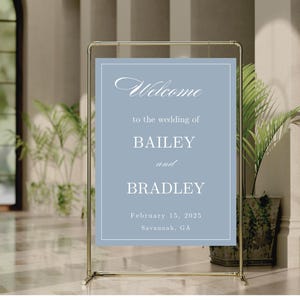 K&ouml;nnte beinhalten: Ein hellblaues Hochzeitsschild mit wei&szlig;em Text. Das Schild lautet "Willkommen zur Hochzeit von Bailey und Bradley, 15. Februar 2025, Savannah, GA".
