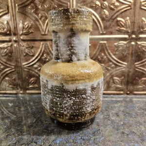 May include: A brown and white ceramic vase with a speckled glaze. The vase has a rounded body and a narrow neck.