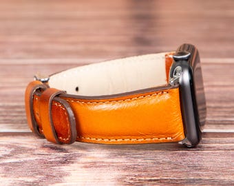 May include: A brown leather watch band with a silver buckle. The band is attached to a black smartwatch.