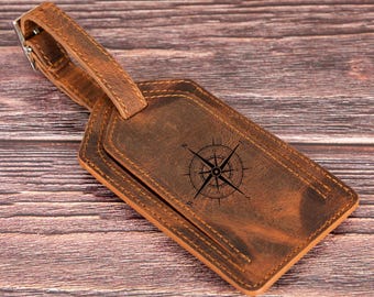 May include: A brown leather luggage tag with a compass design. The tag has a strap for attaching to luggage.