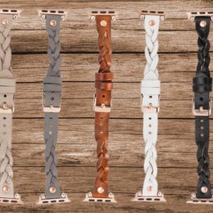 May include: Five braided leather watch bands in different colors: gray, brown, white, black, and beige. The bands are all the same style, with a braided design and a rose gold buckle.