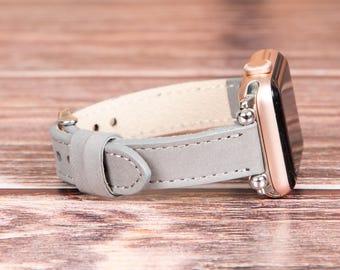 May include: A gray leather watch band with rose gold hardware. The band is designed for a smartwatch.