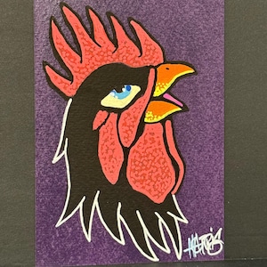 Puede incluir: Ilustración colorida de un gallo sobre un fondo morado. La cabeza del gallo es negra con una cresta y una barbilla rojas. El pico es naranja y amarillo, y el ojo es azul. La obra de arte está firmada en la esquina inferior derecha.