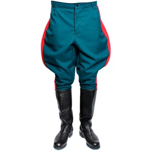 Puede incluir: Pantalones de montar de color turquesa con rayas laterales rojas y botas negras de caña alta.