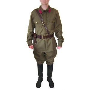 May include: A green military uniform with a brown leather belt and a brown leather strap. The uniform has a red collar and a button-up front.