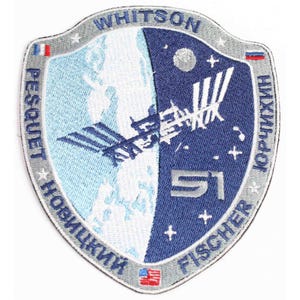 May include: A blue and white embroidered patch with the text "Whitson, Pesquet, Novitskiy, 51, Fischer, Kornienko" and a depiction of the International Space Station.