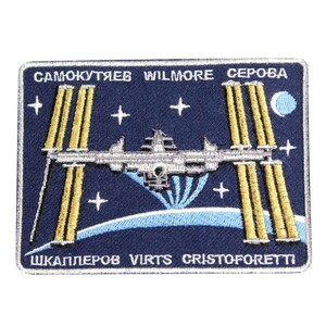 May include: A blue embroidered patch with a white outline depicting the International Space Station orbiting Earth. The patch features the names of the astronauts: Samokutyaev, Wilmore, Serova, Shkaplerov, Virts, and Cristoforetti.