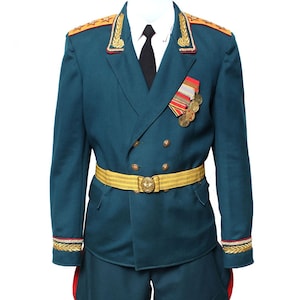 May include: A dark teal military uniform with gold trim and buttons. The uniform has a gold belt with a star-shaped buckle. The uniform also has a red and gold medal on the left side of the chest.