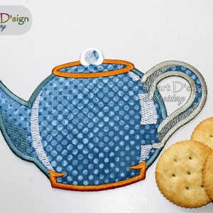 May include: Blue and white polka dot teapot with an orange trim. The teapot is sitting on a white surface with three crackers.