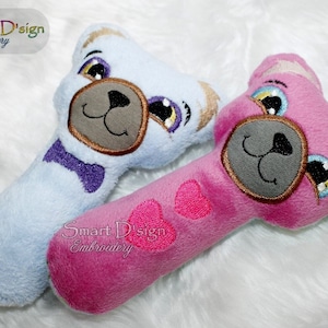 以下が含まれることがあります： 青いクマの顔とピンクのクマの顔が刺繍された、青いベビーラトルとピンクのベビーラトルの2つ。青いラトルには紫色の蝶ネクタイ、ピンクのラトルにはピンクのハートが付いています。