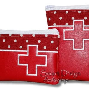 Puede incluir: Dos estuches rojos con cremallera, con lunares blancos y una cruz bordada en blanco. El estuche más grande tiene el texto "Smart D'sign Embroidery" en la parte inferior.