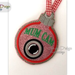 May include: A pink and red Christmas ornament with a green "Mum Cam" text and a black and white camera icon.
