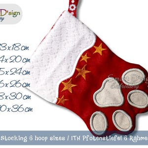 Może przedstawiać: Czerwono-biała świąteczna skarpetka z nadrukiem łapy. Skarpetka jest ozdobiona złotymi gwiazdami i ma biały futerkowy mankiet. Skarpetka jest dostępna w sześciu rozmiarach: 13x18cm, 14x20cm, 15x24cm, 16x26cm, 18x30cm i 20x36cm.