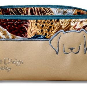 May include: A beige zippered pouch with a brown, white, and blue patterned fabric lining. The pouch has a gray embroidered dog head design on the front and the text "Smart D'sign Embroidery" on the bottom.
