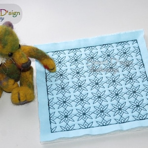 May include: A blue fabric square with a black embroidered design of repeating geometric shapes. The design is a pattern of interlocking stars and squares. The fabric is slightly textured and has a light blue background.