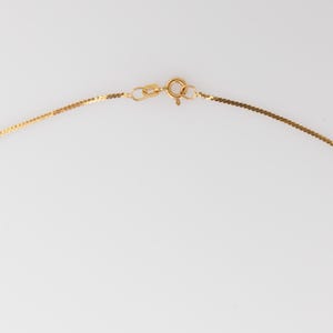 Puede incluir: Un delicado collar de oro con un dise&ntilde;o plano en forma de cadena. El collar presenta un peque&ntilde;o cierre y un anillo de conexi&oacute;n, todo en color oro brillante. El fondo es blanco liso.