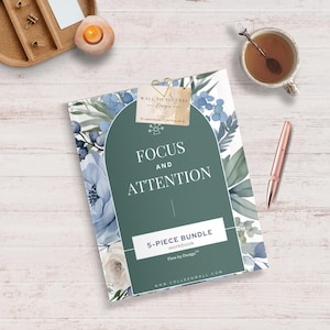 Op de afbeelding: Een werkboek getiteld "Focus and Attention" met een groen boogontwerp en bloemaccenten. De omslag bevat de tekst "5-PIECE BUNDLE workbook" en "Flow by Design". Een roségouden pen, een kopje thee en een kaars zijn ook aanwezig.