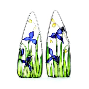 May include: A pair of silver wire earrings with blue and green enamel iris flowers and yellow accents.