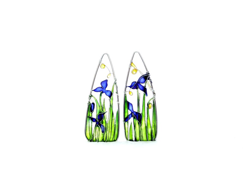 On white background - two triangle frames with a landscape made with thin silver wire. The two pictures are slightly different but have the same style: there are blue iris flowers, light green stems and grass and a touch of yellow golden sunshine.