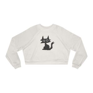 May include: A white cropped sweatshirt with a black silhouette of a cat with large eyes on the front.