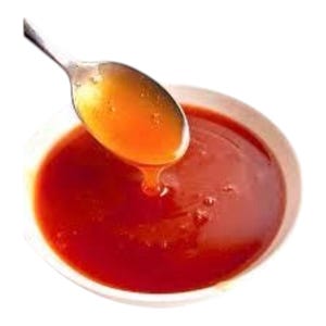 Puede incluir: Primer plano de un cuenco blanco lleno de salsa roja oscura. Una cuchara plateada sostiene una porción de la salsa, con un líquido naranja dorado goteando de ella. La imagen está sobre un fondo blanco.