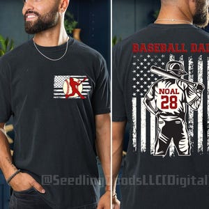 Puede incluir: Camiseta negra con un diseño de bandera americana roja, blanca y azul. La bandera tiene una silueta de jugador de béisbol con el texto "Baseball Dad" y "Noal 28" en ella.
