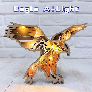 May include: A wooden eagle with a mountain and forest scene inside, illuminated by warm white LED lights. The eagle is flying with its wings spread wide. The text "Eagle A+Light" is displayed above the eagle.