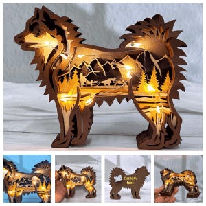 May include: A wooden silhouette of a dog with a mountain scene inside. The dog is lit up with warm white fairy lights. The silhouette is made of multiple layers of wood, creating a 3D effect. The dog is standing on a wooden base.