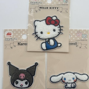 May include: Three iron-on patches featuring Hello Kitty, Kuromi, and Cinnamoroll. The patches are white, black, and white, respectively. The patches are packaged on individual cards with Japanese text.