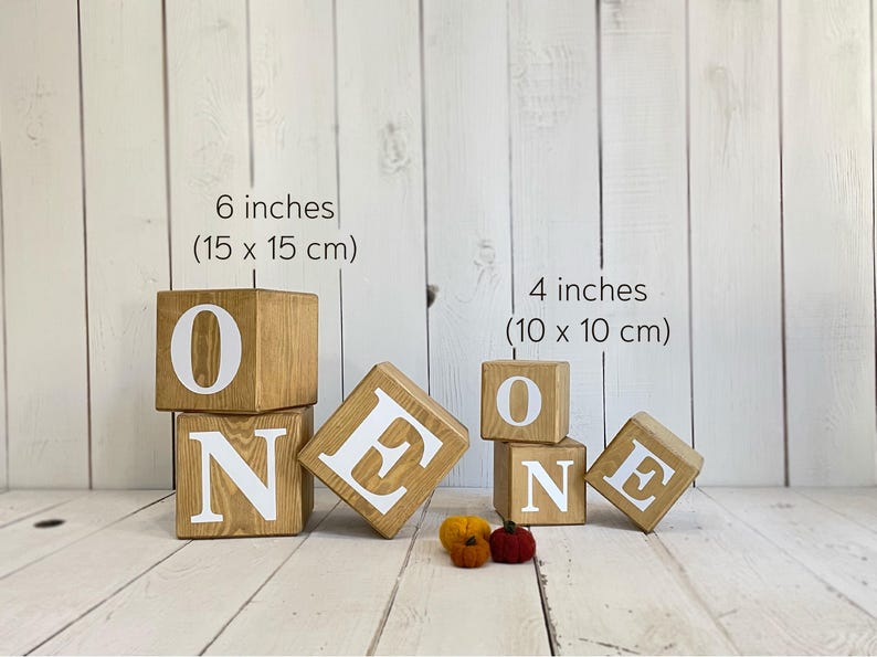 May include: Wooden blocks spelling out the word "ONE" in white letters. The blocks are 6 inches (15 cm) and 4 inches (10 cm) in size.